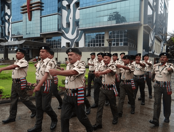 SUN SECURITY SERVICES team marching in formation in front of modern building
